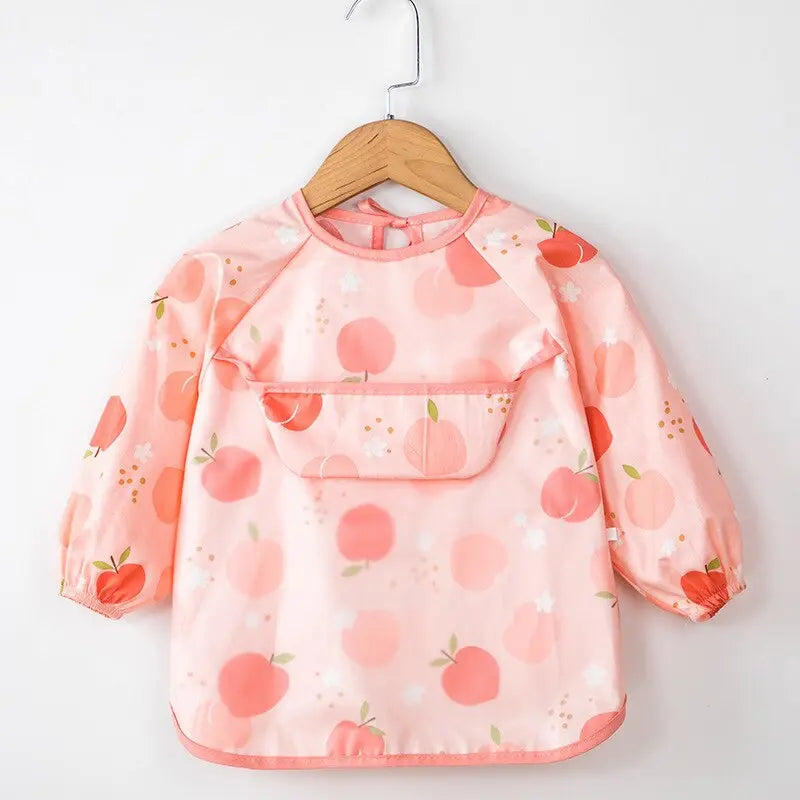 Petite fille sur une chaise haute portant un bavoir intégral à manches longues rose imperméable pour le repas,